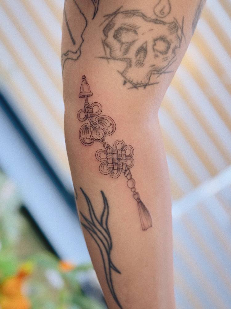 Norigae tattoo in illustrative style done on the forearm.