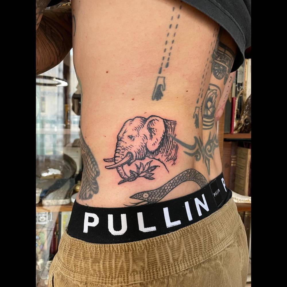 Engraving style elephant portrait tattoo located on the waist.