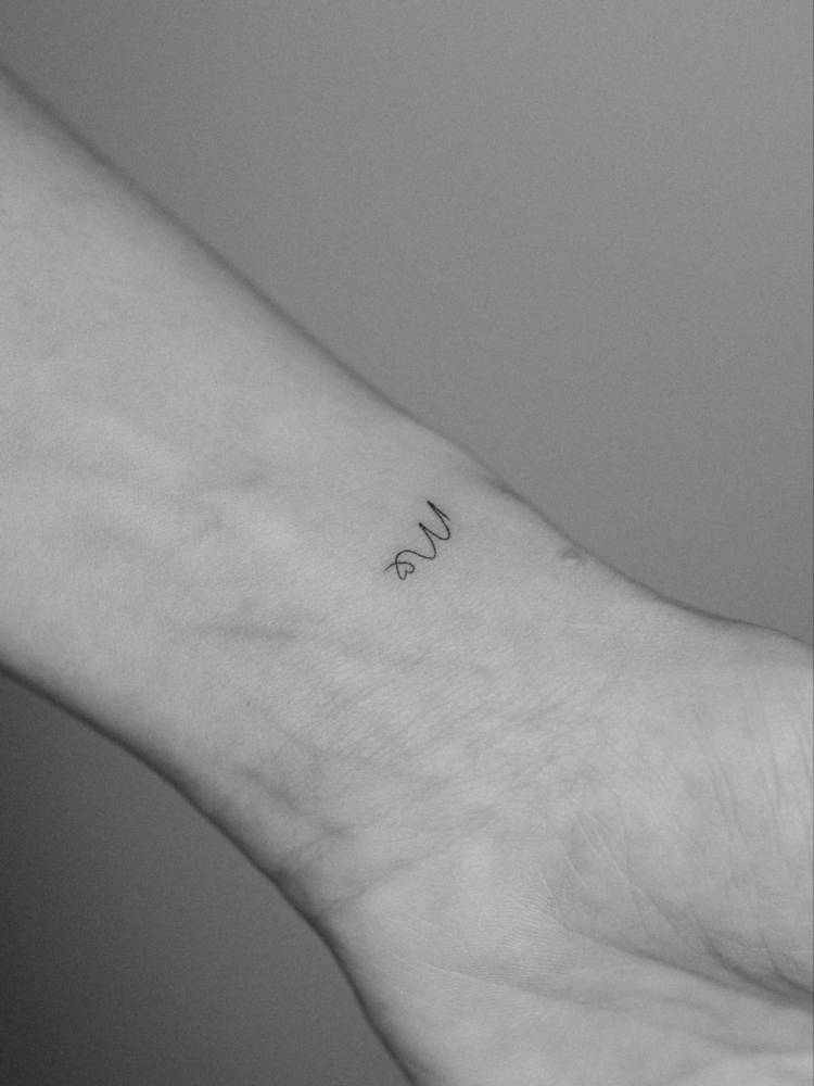 Letter "M" and heart tattoo in minimalistic style placed on the wrist.