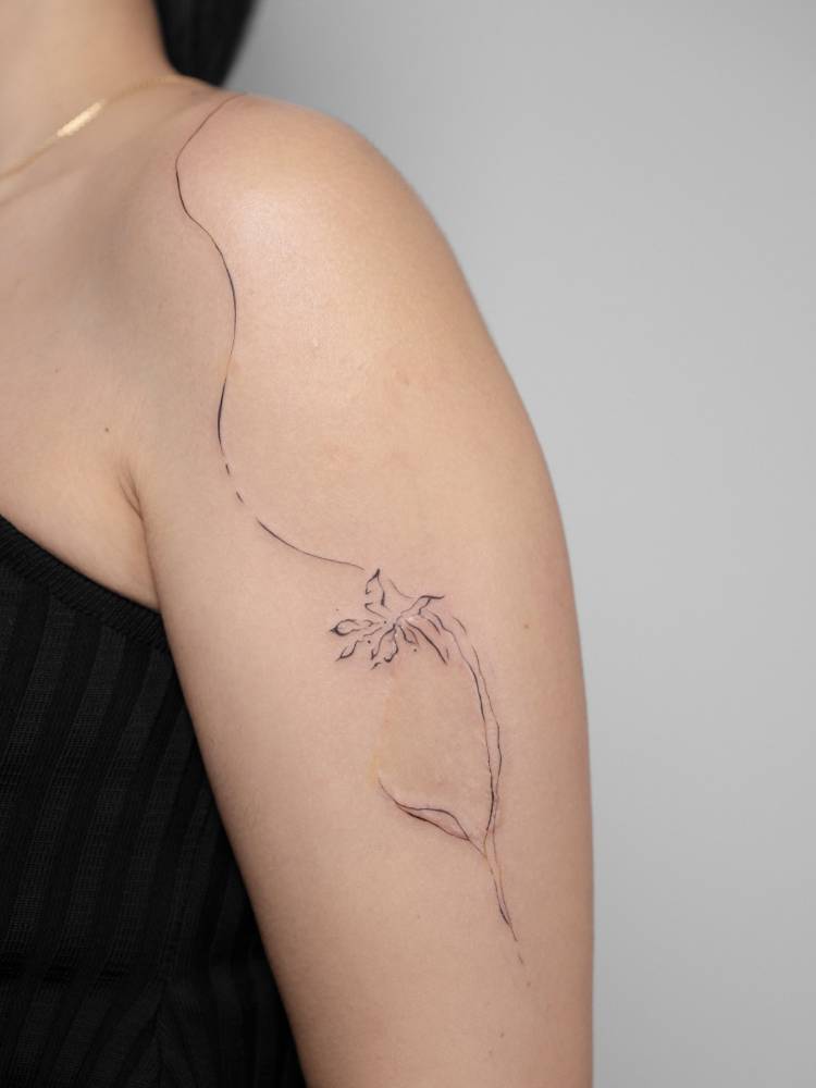 Abstract flower tattoo in line art style done on the upper arm.