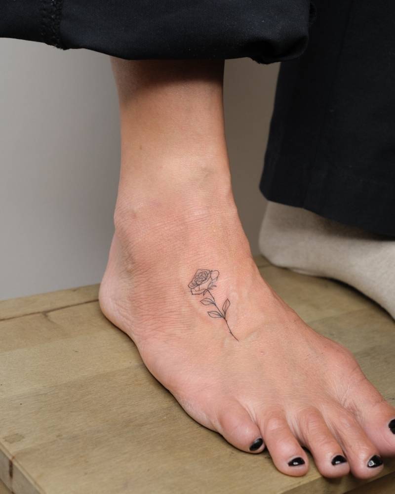 Little rose tattoo placed on the foot, done in fine line style.
