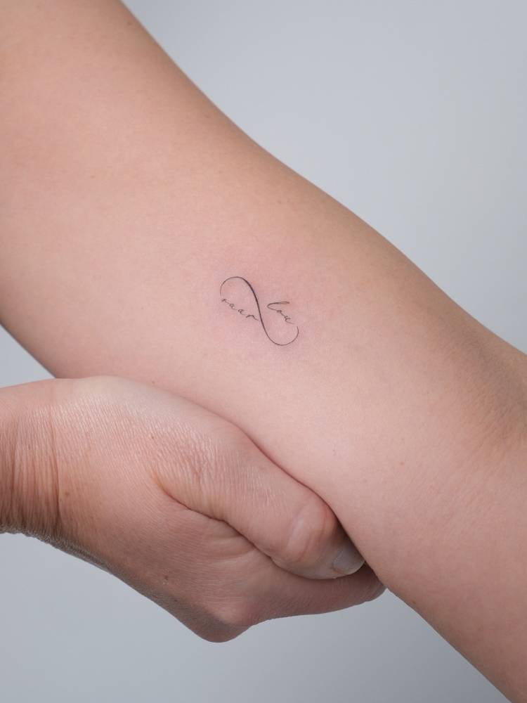 Infinity symbol and names tattooed on the inner arm.