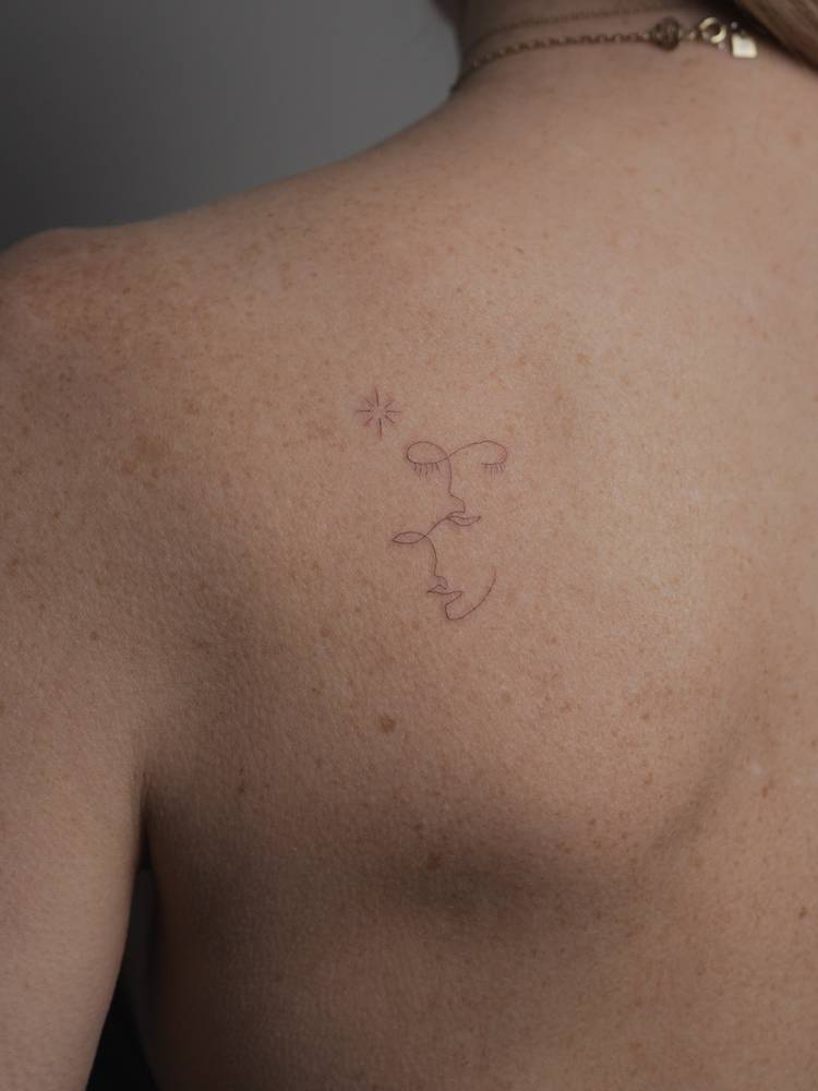 Single needle faces tattoo located on the shoulder blade.