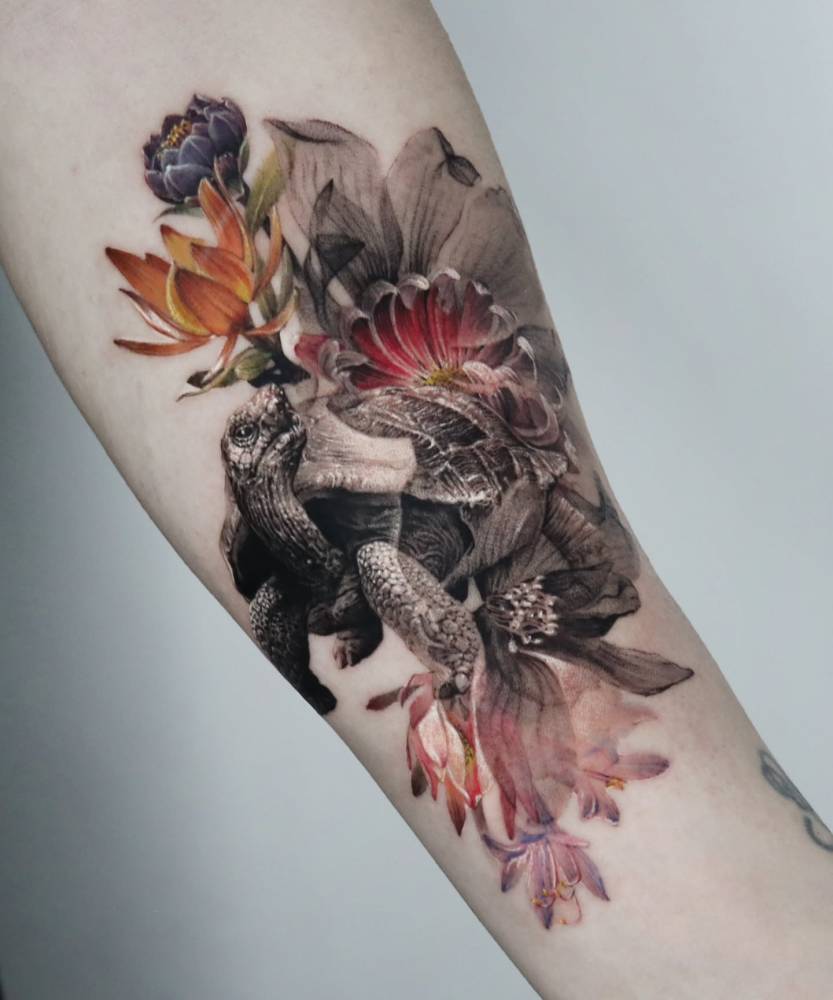 Tortoise and flowers tattooed on the inner forearm, done in micro-realism.