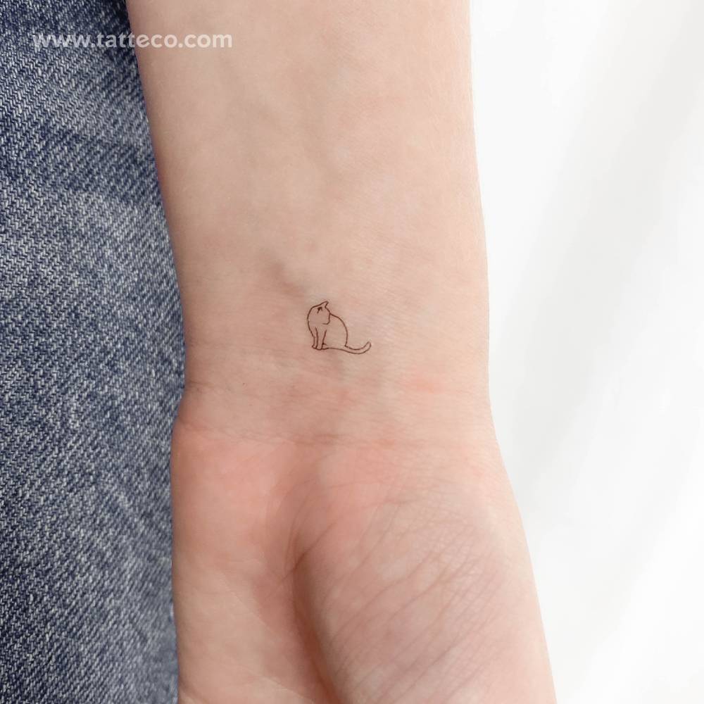 Tiny fine line cat temporary tattoo located on the wrist.