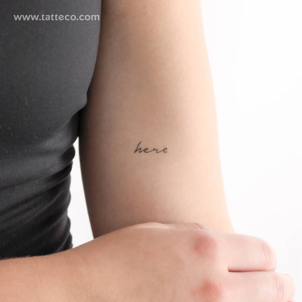 Handwritten font word "here" temporary tattoo located on the inner arm.
