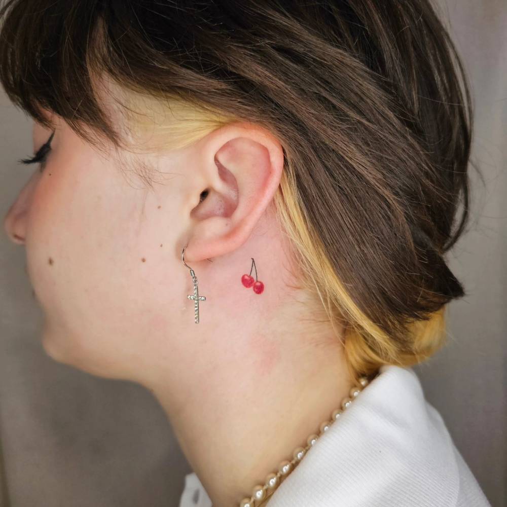 Minimalistic style cherries tattooed behind the ear.