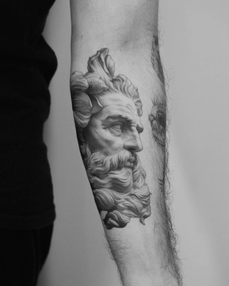 Bust of Neptune tattoo located on the inner forearm, black and grey style.