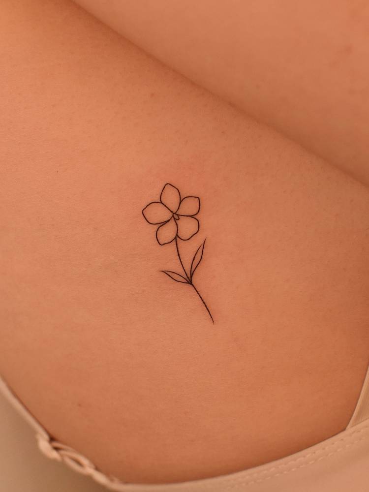 Fine line style flower tattoo located on the rib.