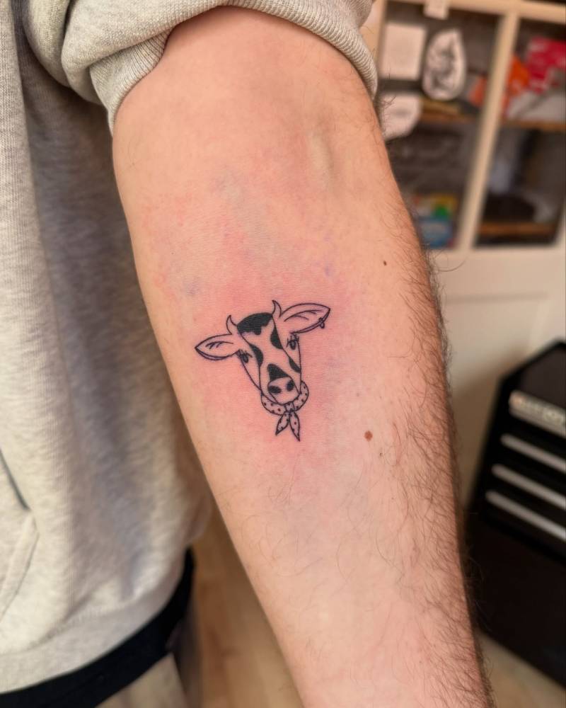 Cow portrait tattoo in illustrative style located on the inner arm.