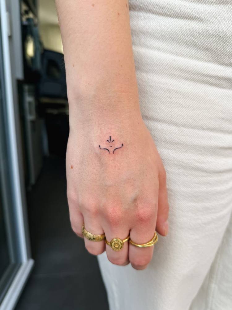 Minimalistic little ornament tattooed on the hand.