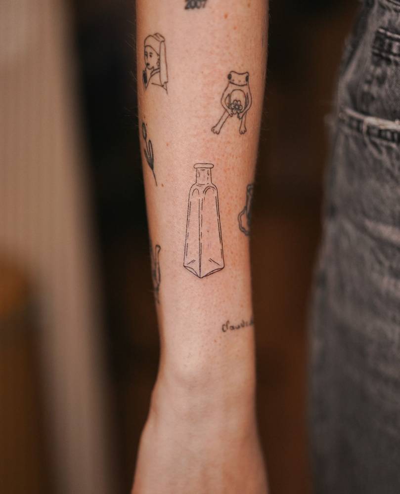 Fine line style bottle tattoo located on the forearm.