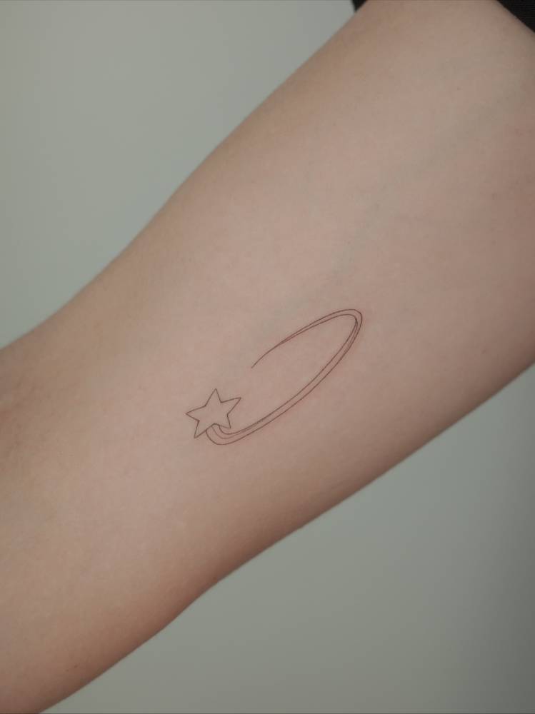 Shooting star tattoo placed on the inner arm, fine line style.