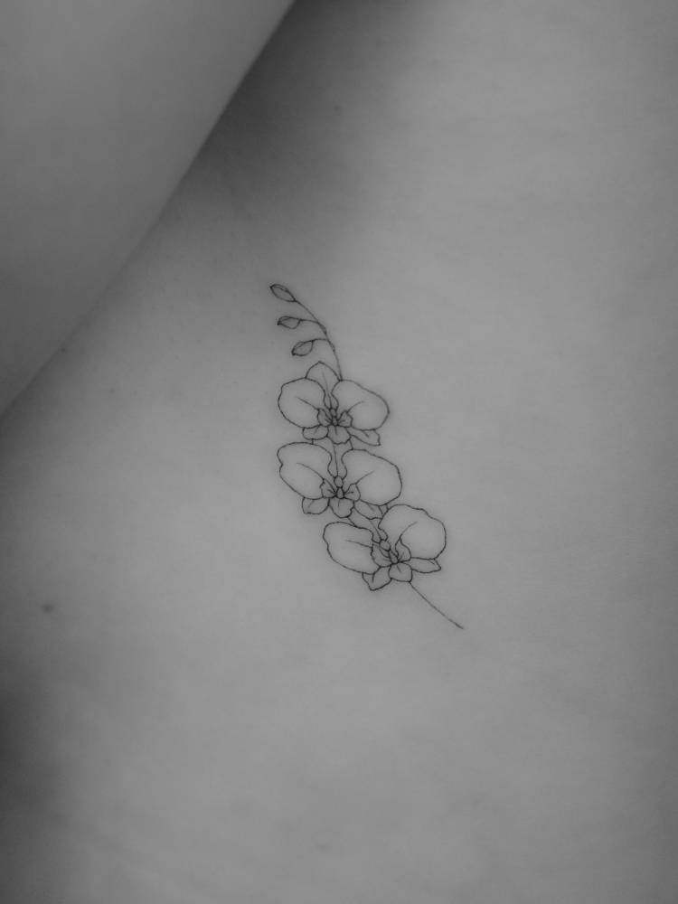 Orchids tattoo in fine line style located on the side boob.