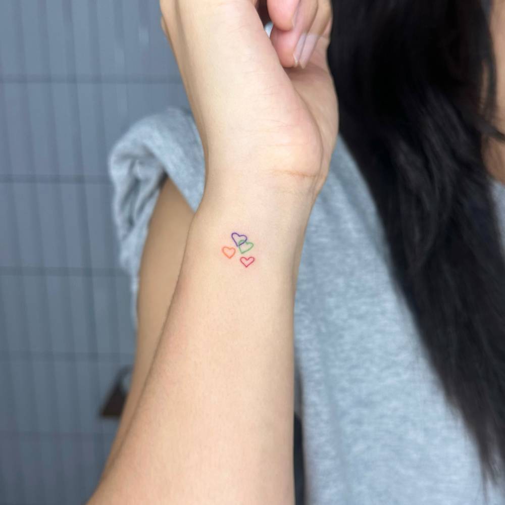 Colorful minimalistic hearts tattoo located on the wrist.