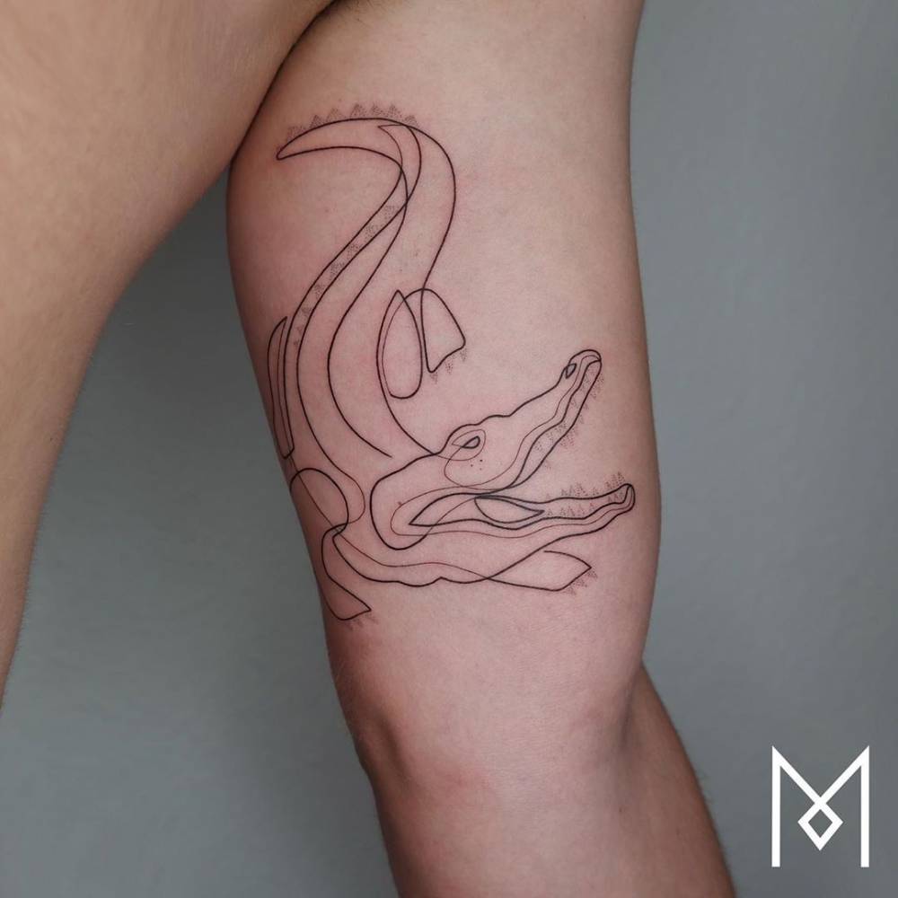 Continuous line alligator tattoo located on the inner arm.