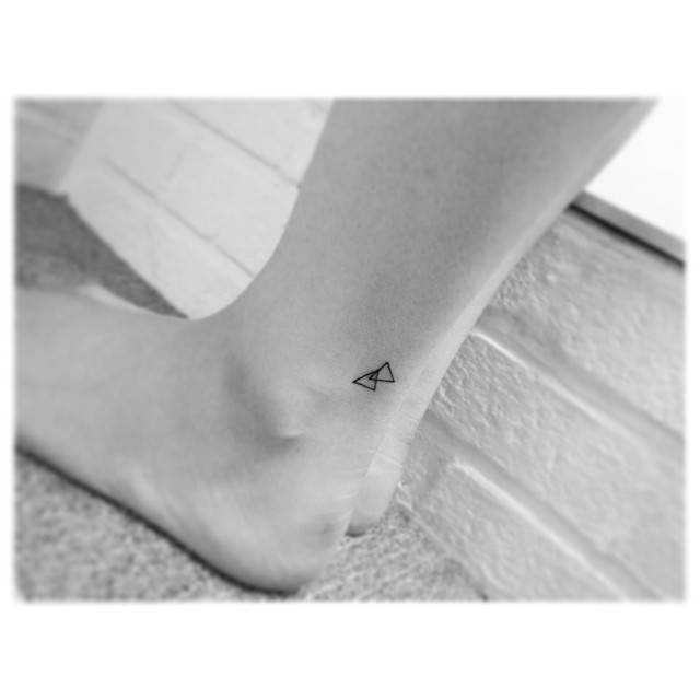 Tiny minimalistic triangles tattooed on the ankle.