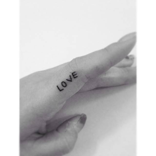 Handwritten font word "love" tattooed on the finger.