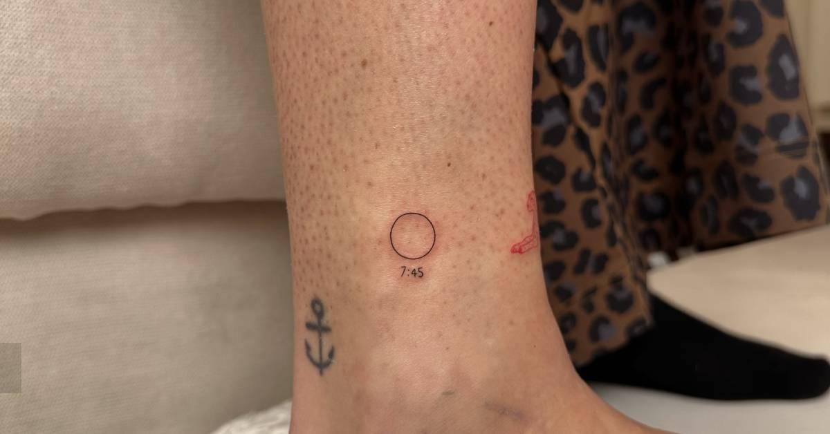 Minimalistic style circle and hour tattoo located on