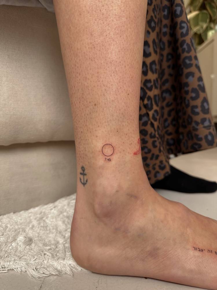 Minimalistic style circle and hour tattoo located on the ankle.