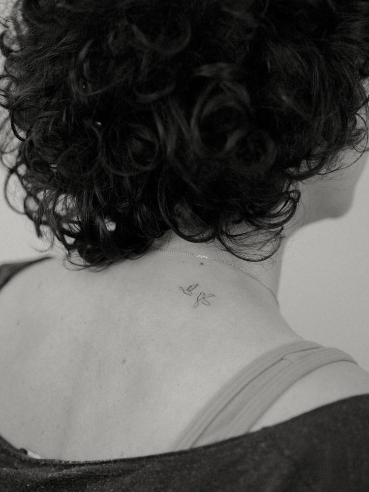 Tiny flying birds tattoo in fine line style done on the upper back.
