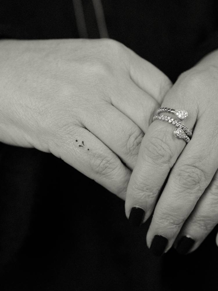 Tiny ornament design tattooed on the finger, minimalistic style.