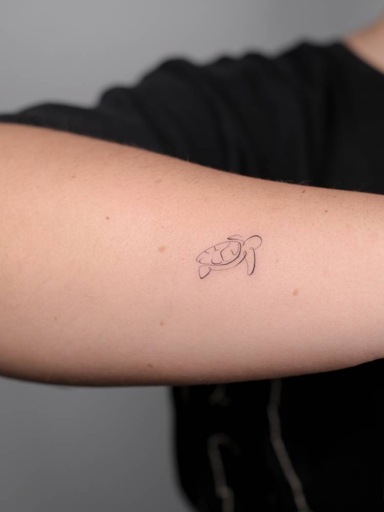 Continuous line little turtle tattoo located on the forearm.