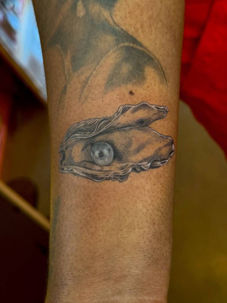 Oyster tattoo in illustrative style located on the wrist.