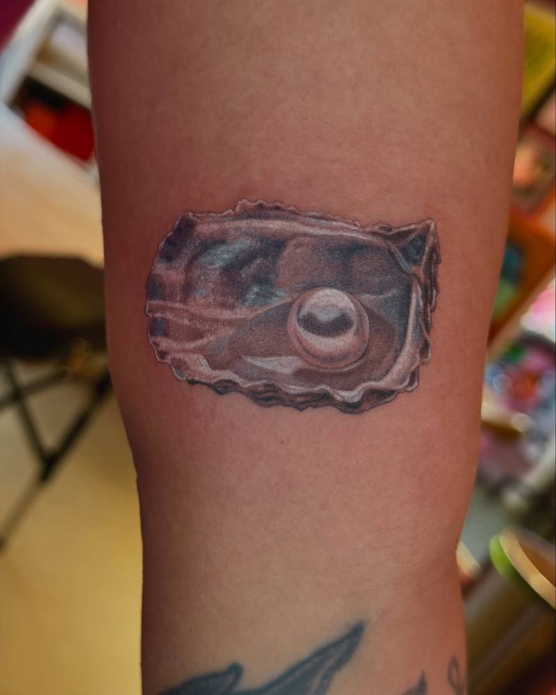 Oyster tattoo in illustrative style located on the inner arm.