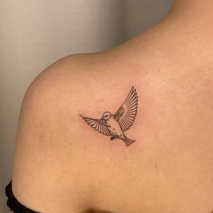 Fine line bird tattoo on the shoulder blade