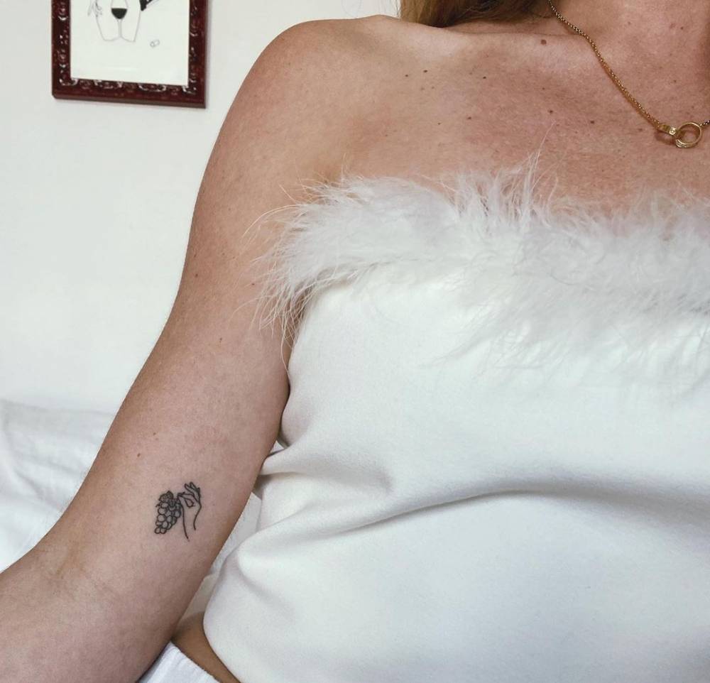 Hand poked grapes tattoo on the inner arm.