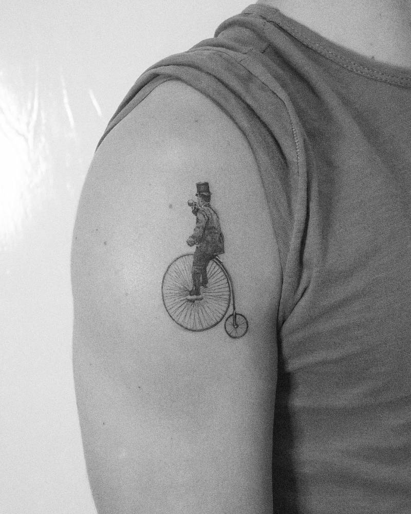 Micro-realistic penny-farthing tattoo  on the shoulder.