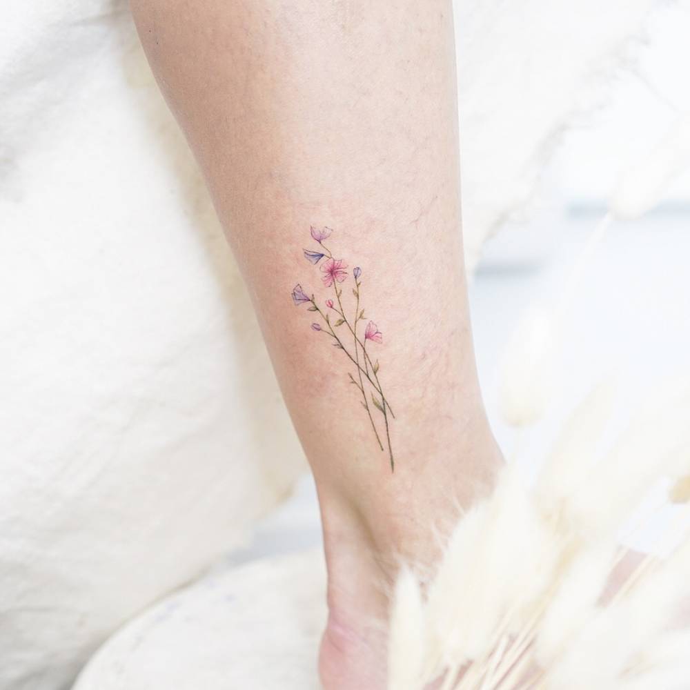 Watercolor flower tattoo on the ankle.