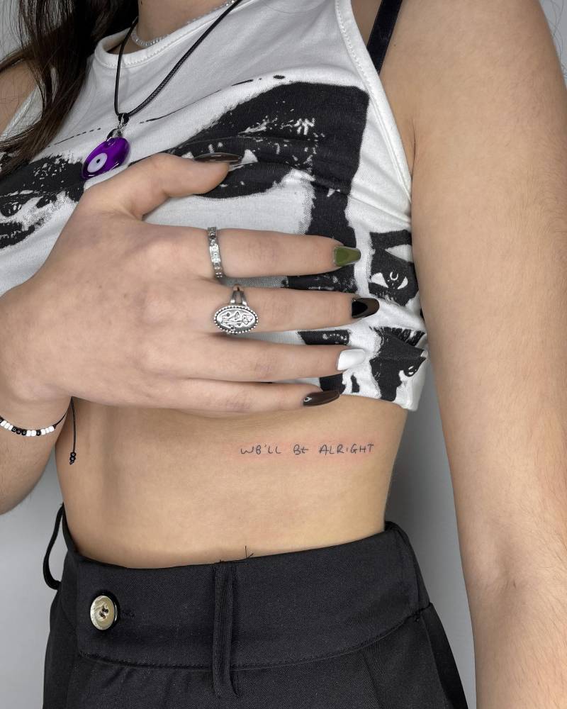 "We'll be alright" lettering tattoo handwritten on the rib.