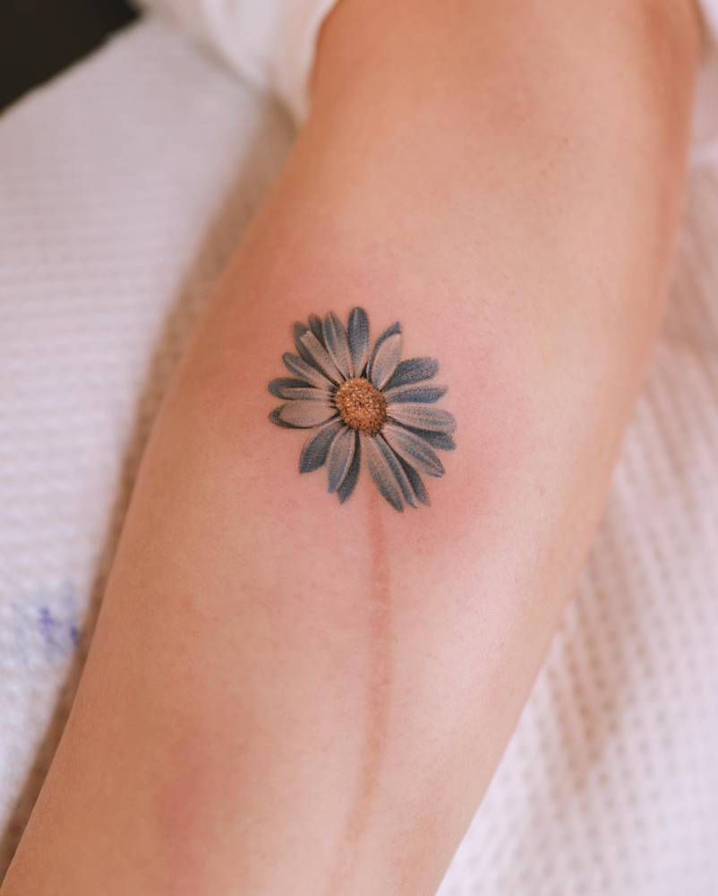 Scar cover up daisy tattoo done on the inner forearm.