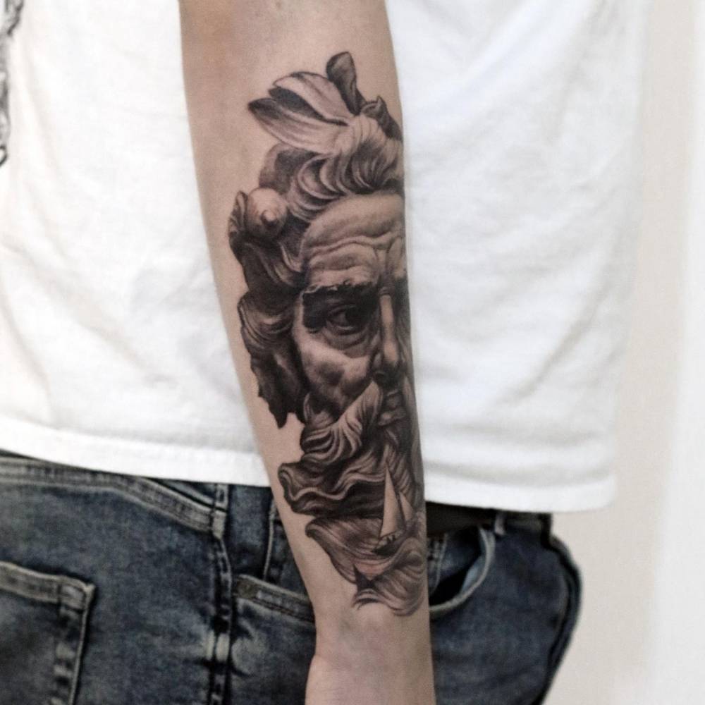 Black and grey Bust of Neptune (Poseidon) tattoo located on the forearm.