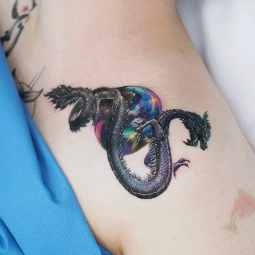 Realistic style dragon tattoo located on the shoulder.