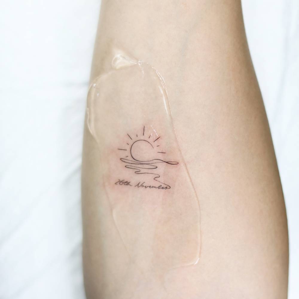 Sea sunset and date tattoo located on the inner forearm.