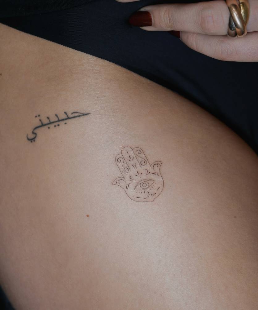 Fine line style hamsa tattoo located on the thigh.