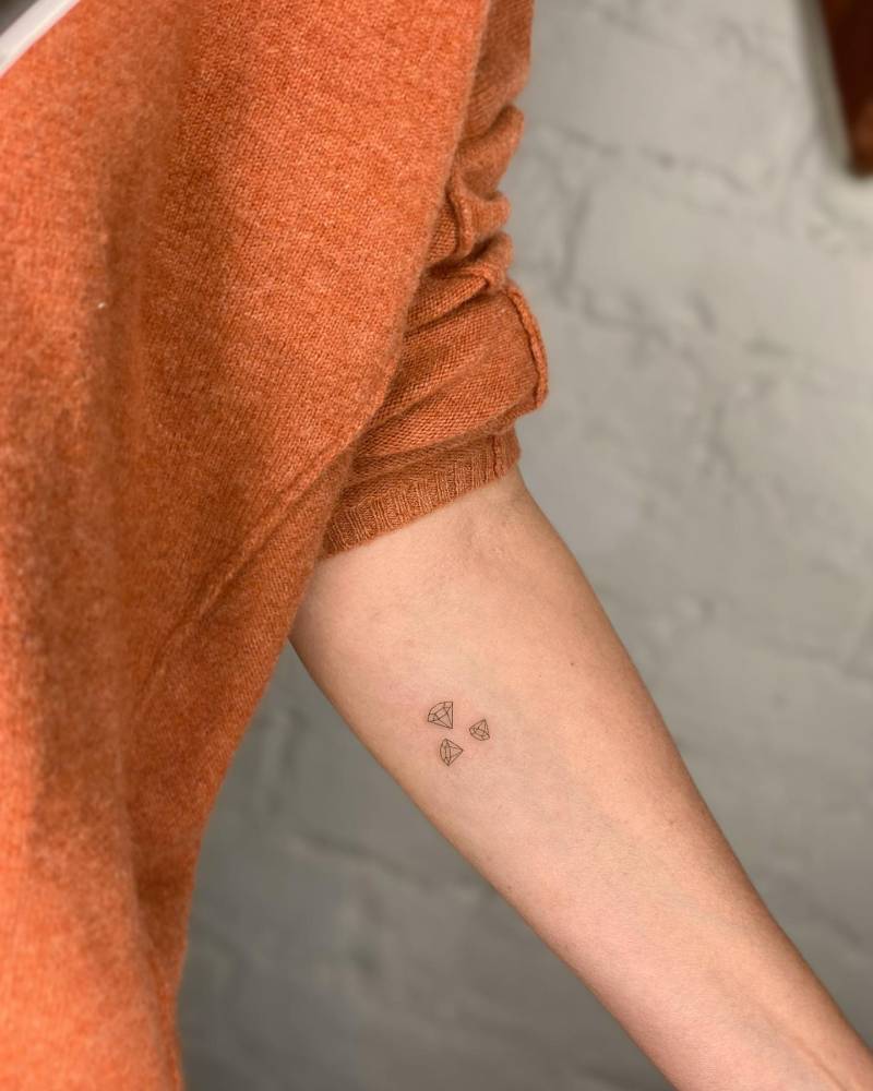 Tiny diamonds tattoo located on the inner forearm, done in fine line style.