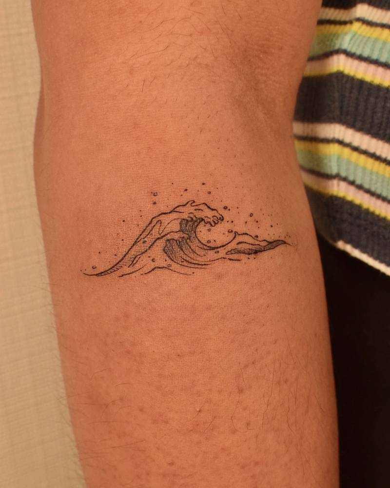 Little wave tattoo in illustrative style located on the forearm.