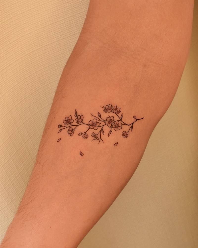 Illustrative style cherry blossom tattoo located on the inner forearm.