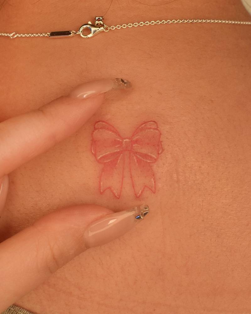 Illustrative style bow tattoo located on the upper back.