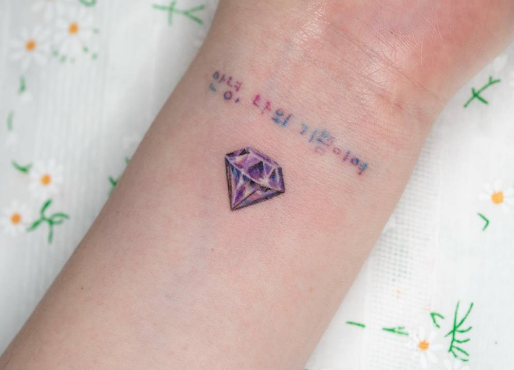 Amethyst gemstone tattoo in micro-realistic style placed on the wrist.