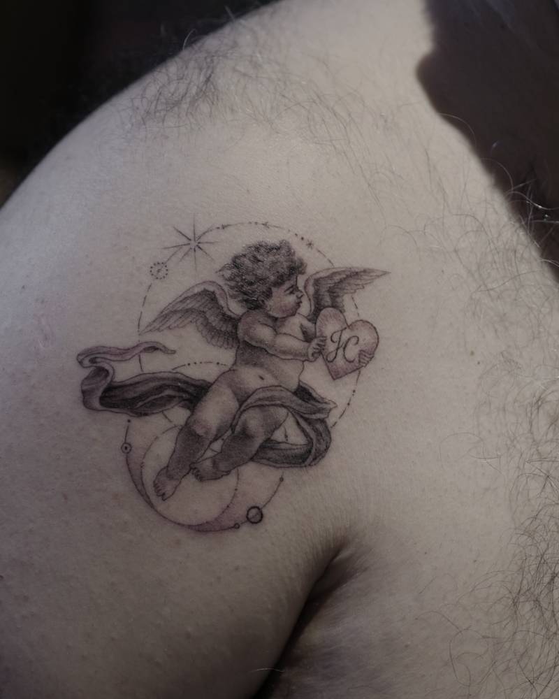 Classical style cherub tattoo located on the shoulder.