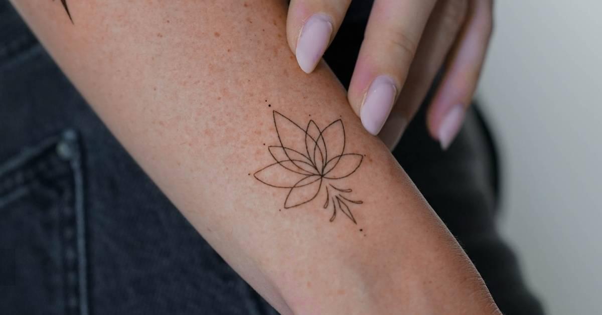 Fine line style lotus flower tattoo located on the