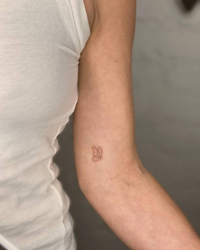 One line butterfly tattoo located on the inner arm.