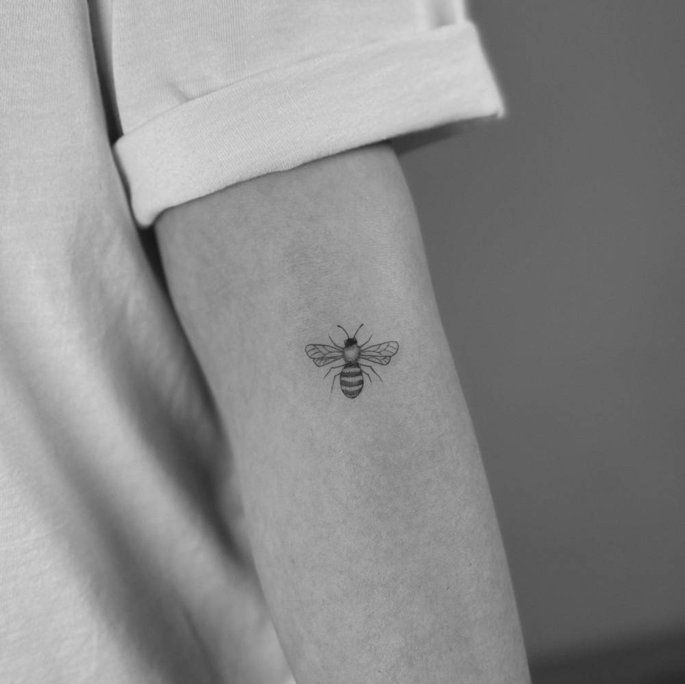 Illustrative style bee tattoo located on the forearm.