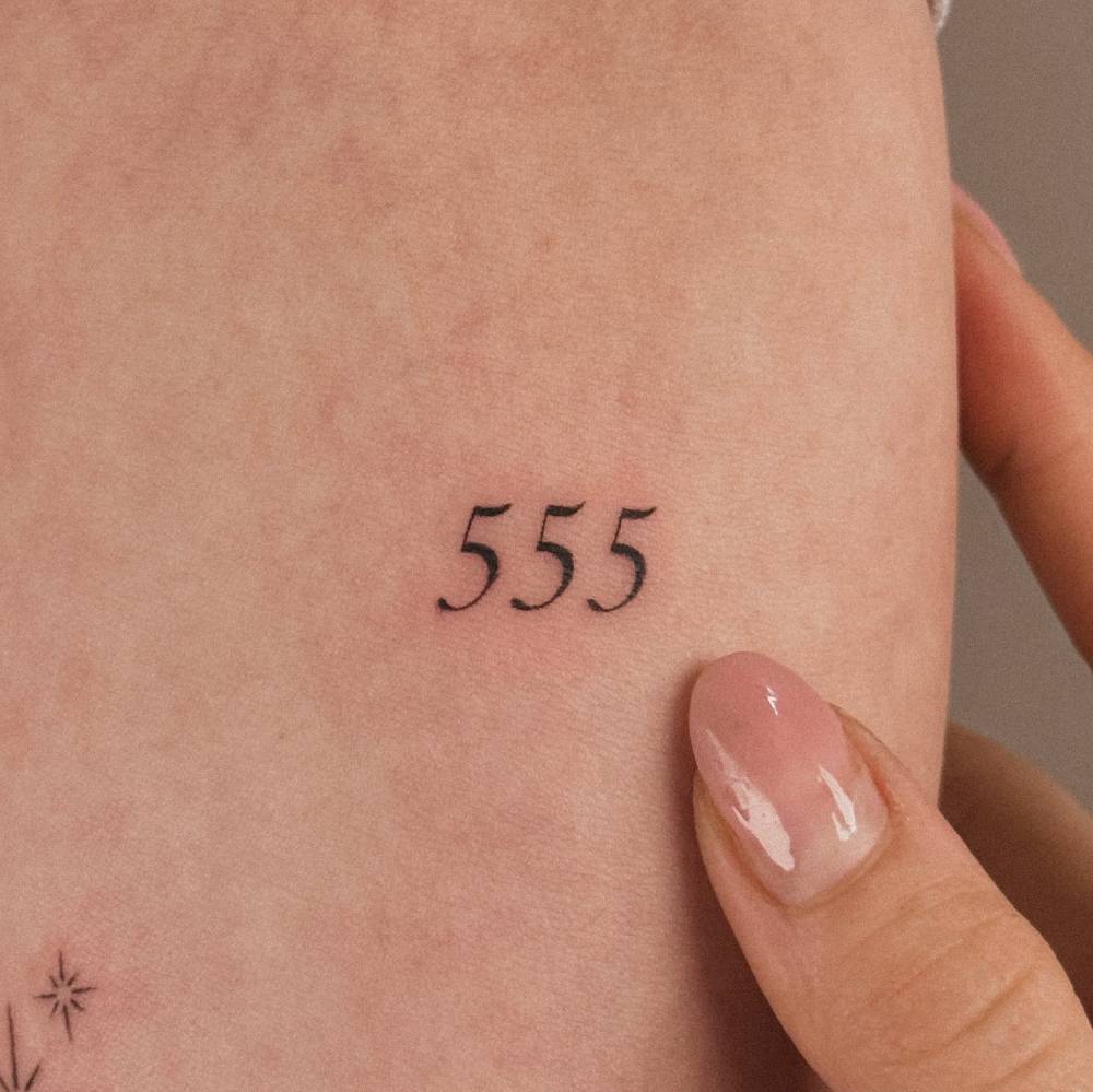 Angel number "555" tattooed on the inner forearm.