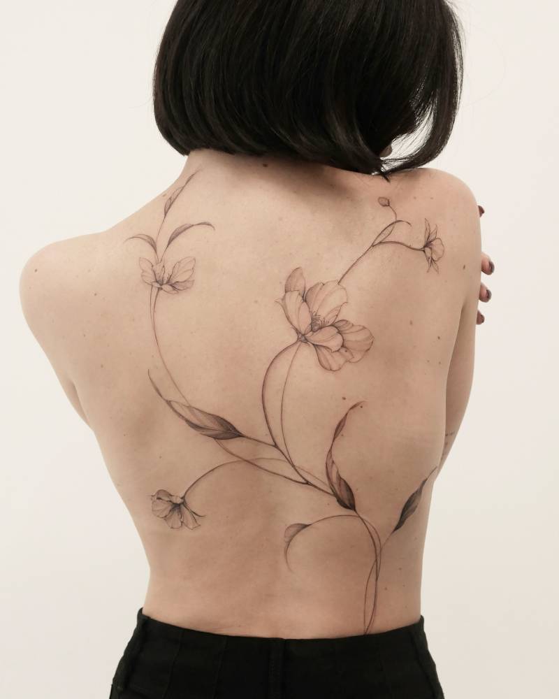 Flower collection tattooed on the back, done in illustrative style.